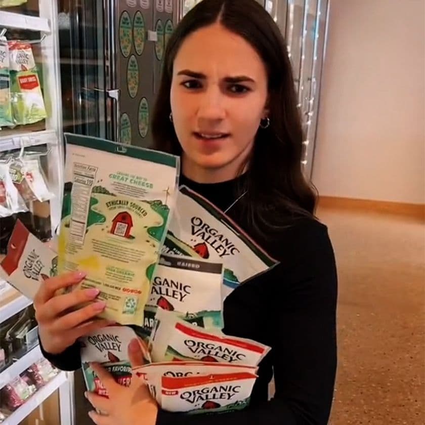 Organic Valley employee holding several bags of Organic Valley Cheese.